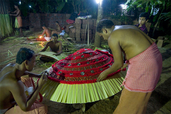 Workers preparing the god's costume using richly coloured fabrics