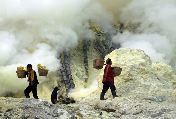 A miner with sulfur laden baskets. The other descends into the fumes for his share.
