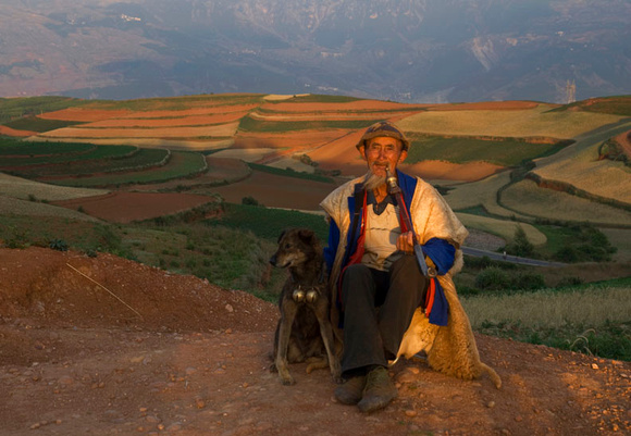 9. An elderly farmer donning his sheepskin coat relaxes near his farmland
