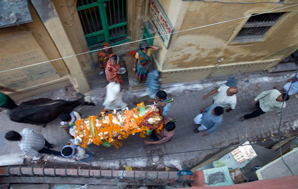 The pall bearers carrying a shrouded corpse through the serpentine lanes of Varanasi towards Manikarnika, the ghat of death.