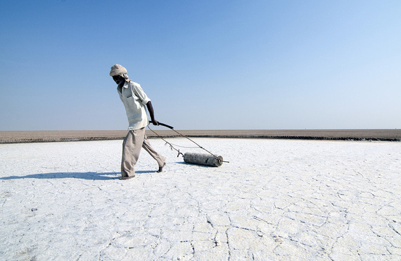 Davalram, 64, leveling the salt pan his family has worked